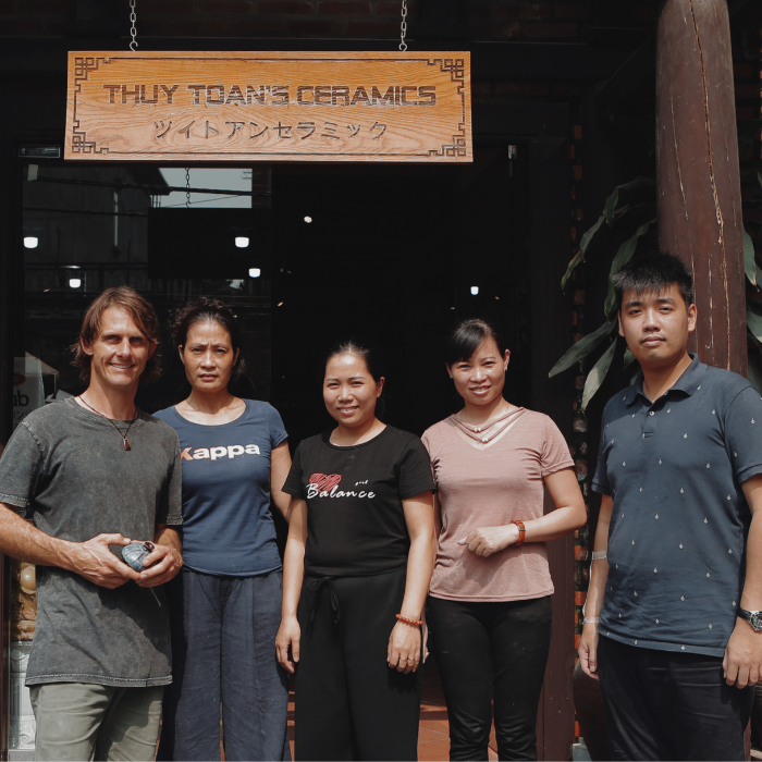Five People Standing Outside Ceramic Pottery Studio Under Sign That Reads Toan Family Studio