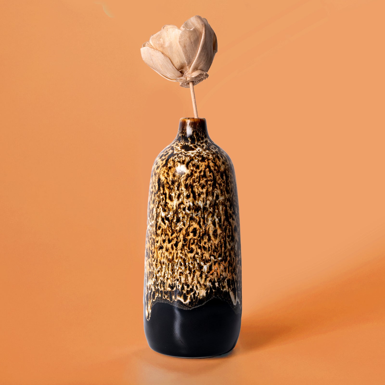 Pottery For The Planet eco-friendly home decor vase with textured brown and black glaze holding a dried flower