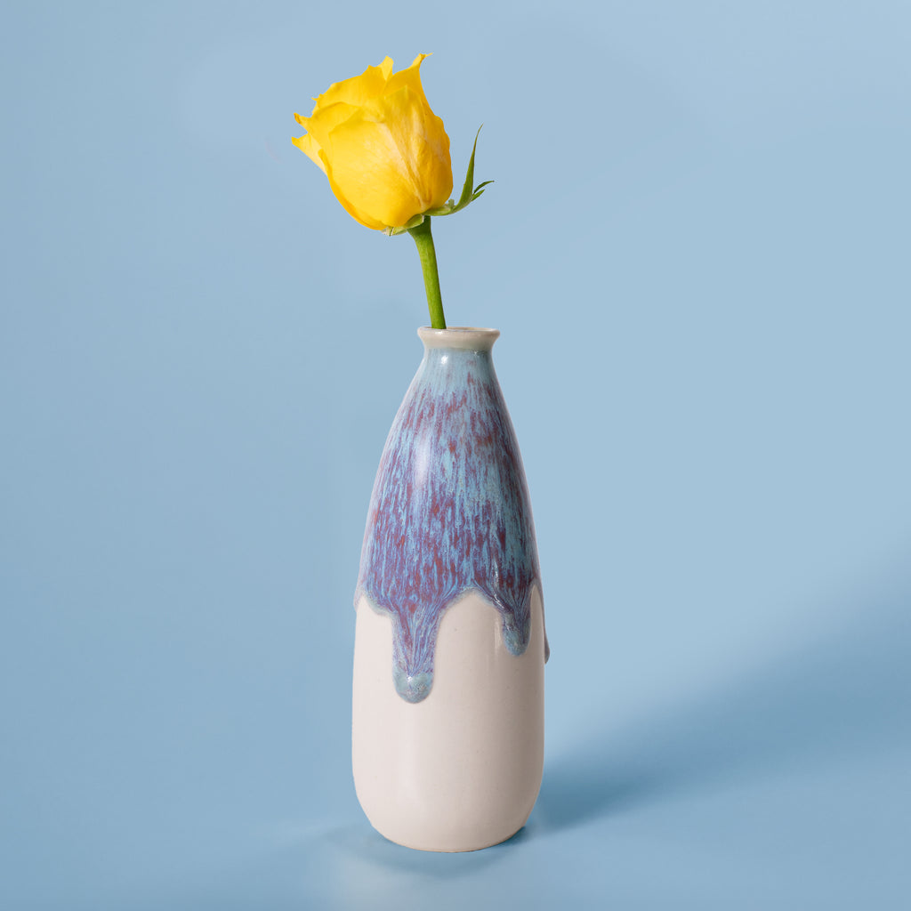 Artisan decorative vase for flowers with blue and white glaze holding a single yellow rose
