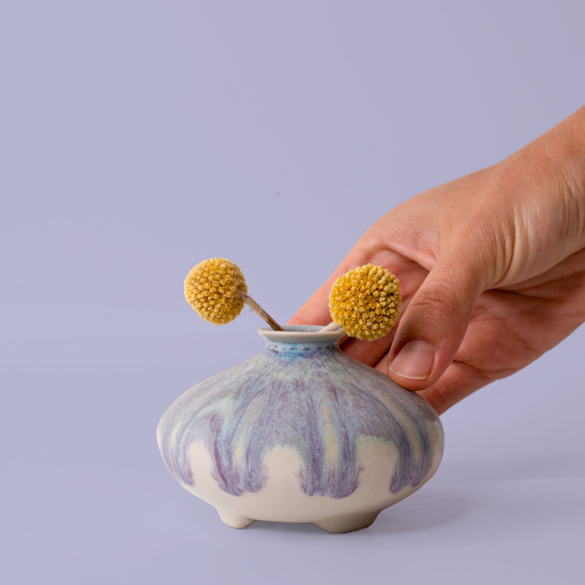 Pottery For The Planet artisan decorative vases with blue and white glaze held by hand with yellow billy balls