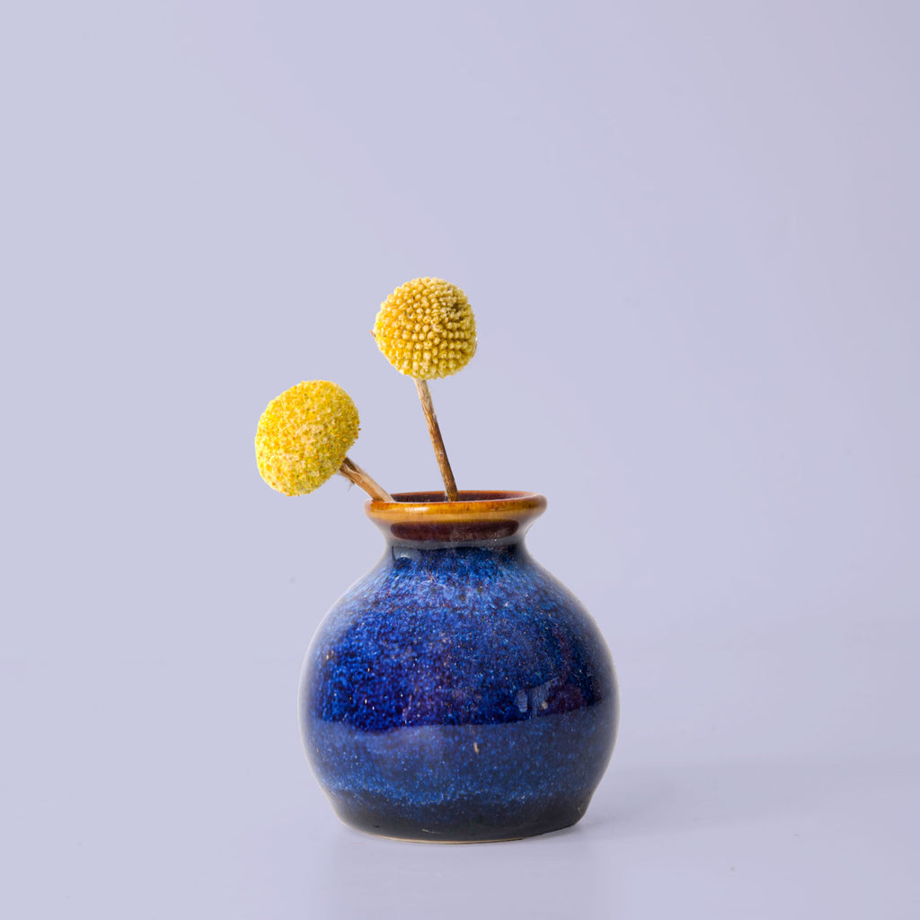 Pottery For The Planet blue ceramic eco-friendly home decor vase with two yellow billy button flowers