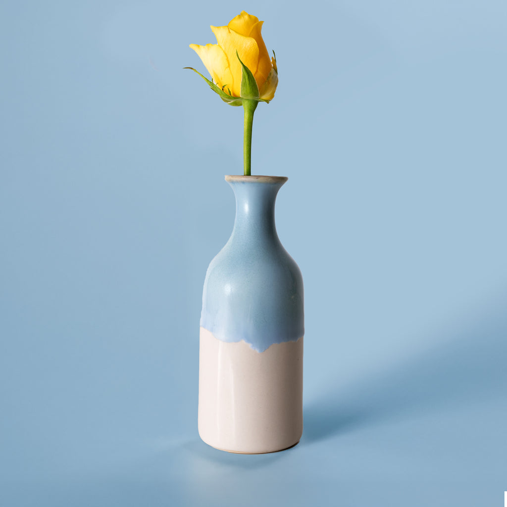 Small handmade flower vase by Pottery For The Planet with blue and beige glaze holding a yellow rose