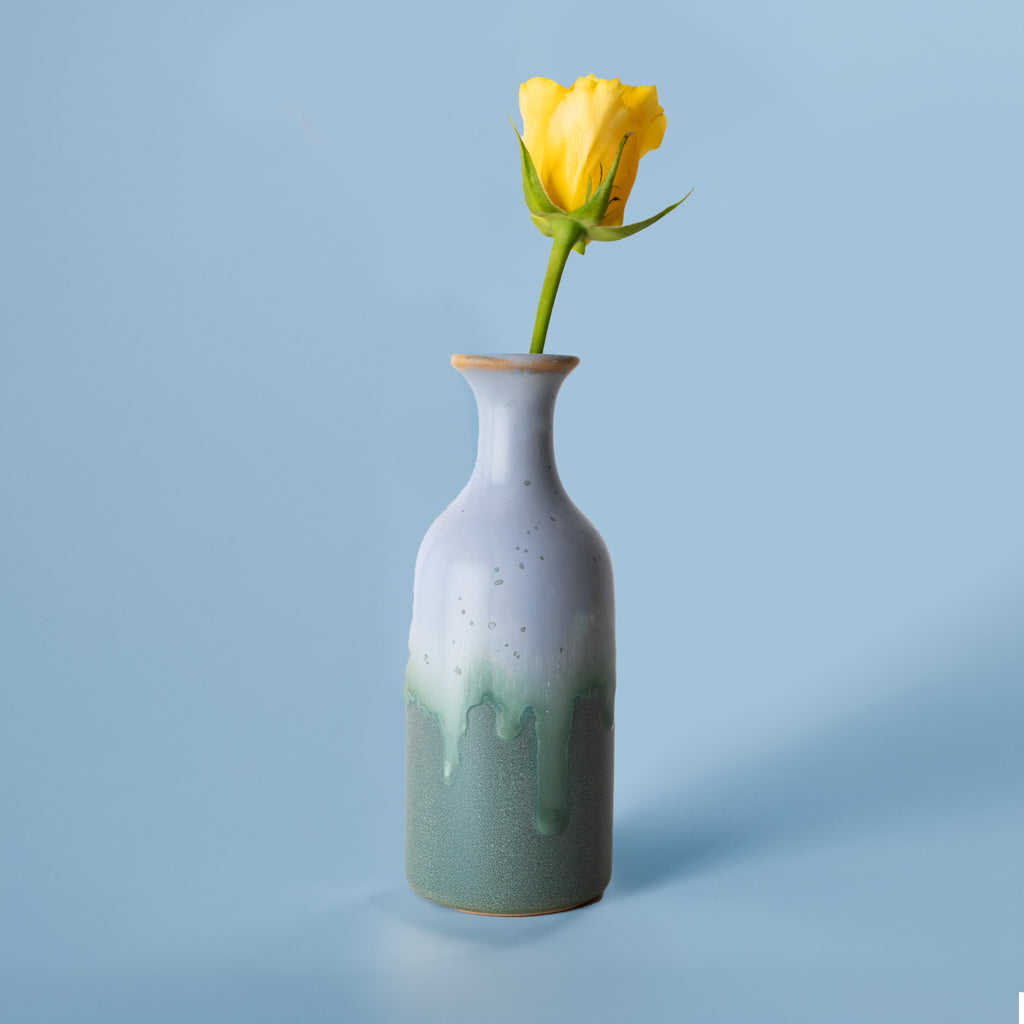 Pottery For The Planet small handmade flower vase in green and white glaze with a yellow rose on blue background