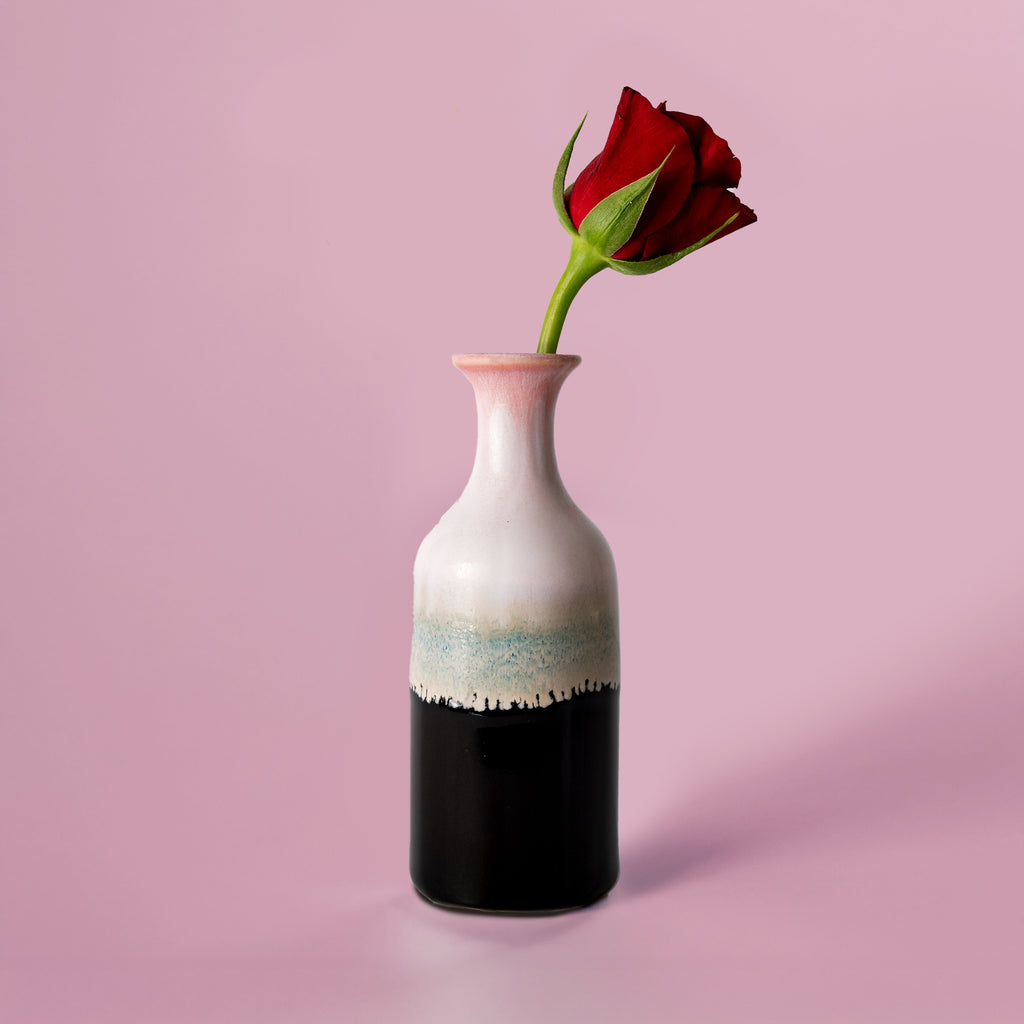 Small handmade flower vase by Pottery For The Planet with a red rose on pink background