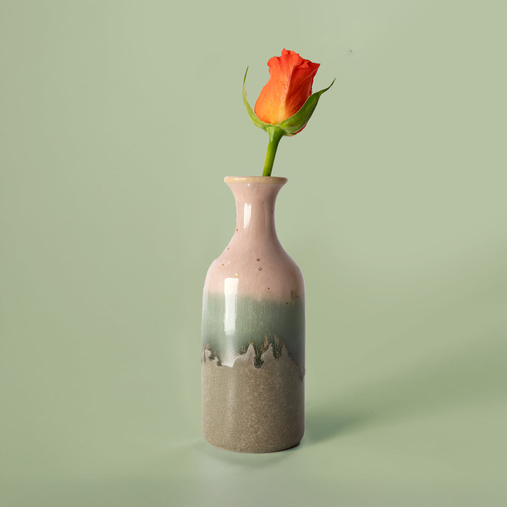 Small handmade flower vase by Pottery For The Planet with pink green and brown glaze holding an orange rose