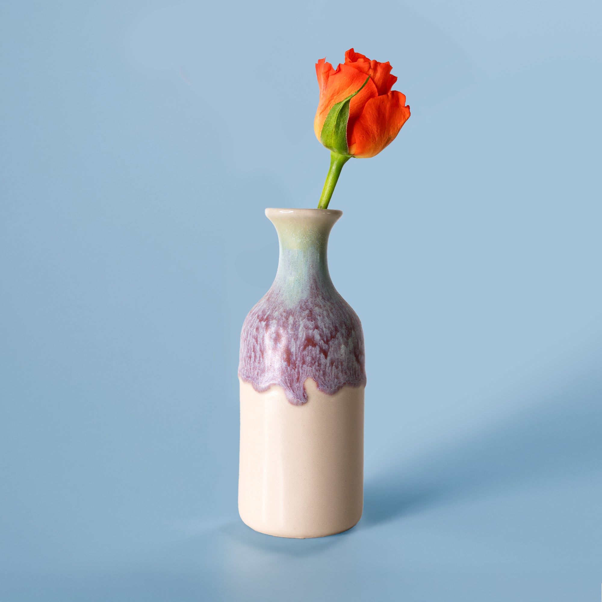 Small handmade flower vase by Pottery For The Planet with a purple glaze and a single orange rose