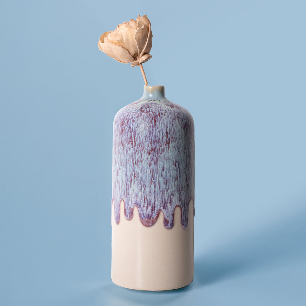 Pottery For The Planet medium decorative bud vase with purple drip glaze and dried flower on blue background