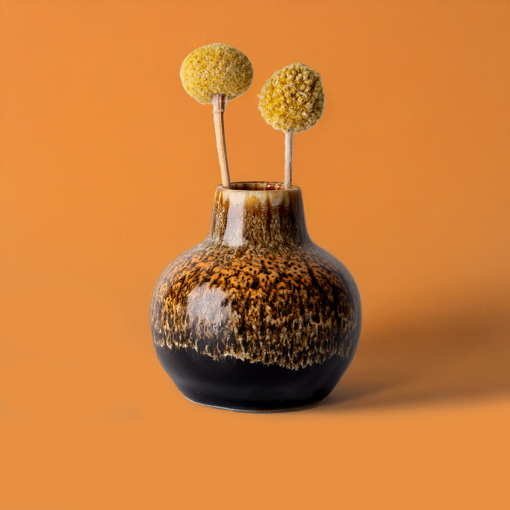 Small handmade home decor vase by Pottery For The Planet with brown and black glaze holding dried yellow flowers