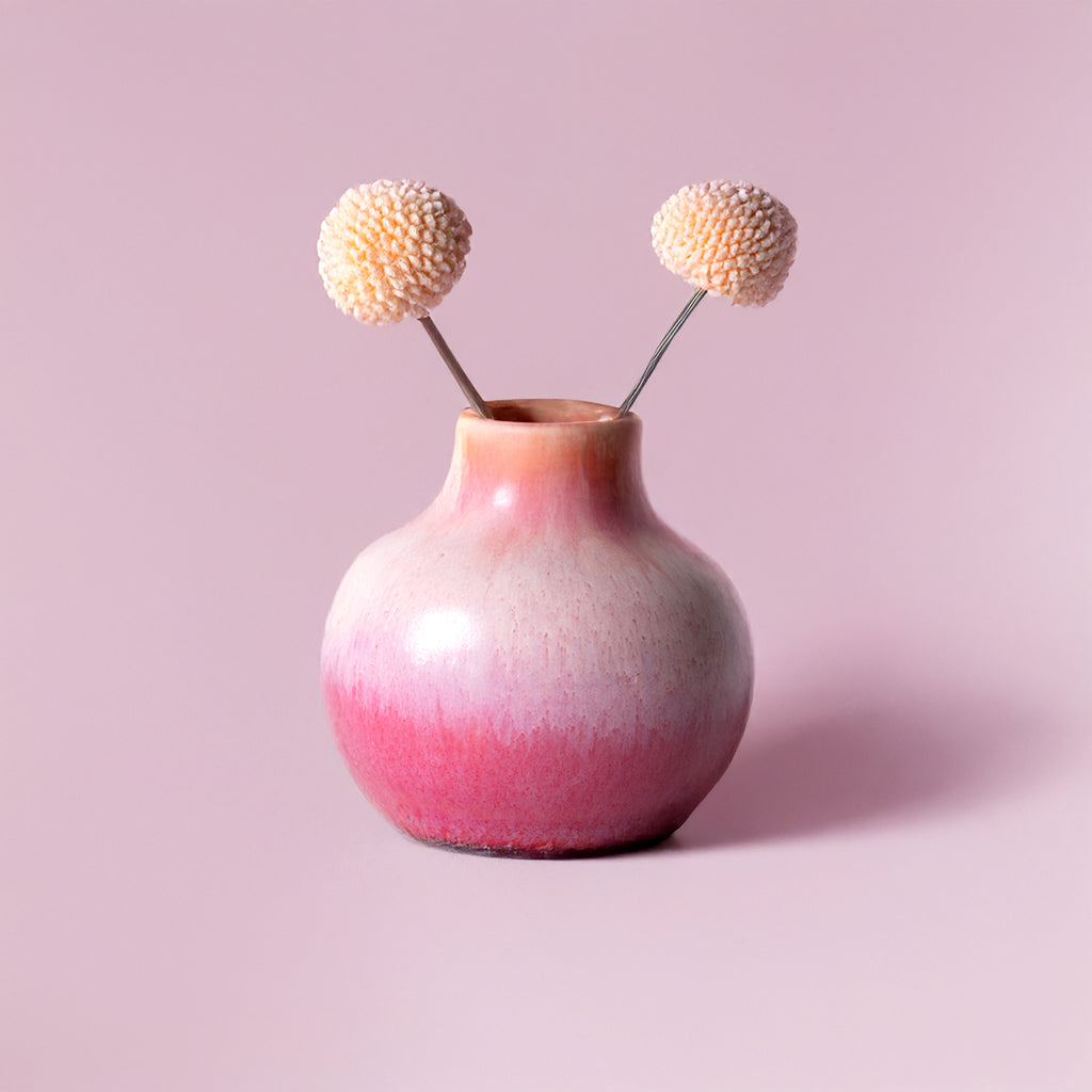 Small handmade home decor vase by Pottery For The Planet with pink gradient and two dried flowers