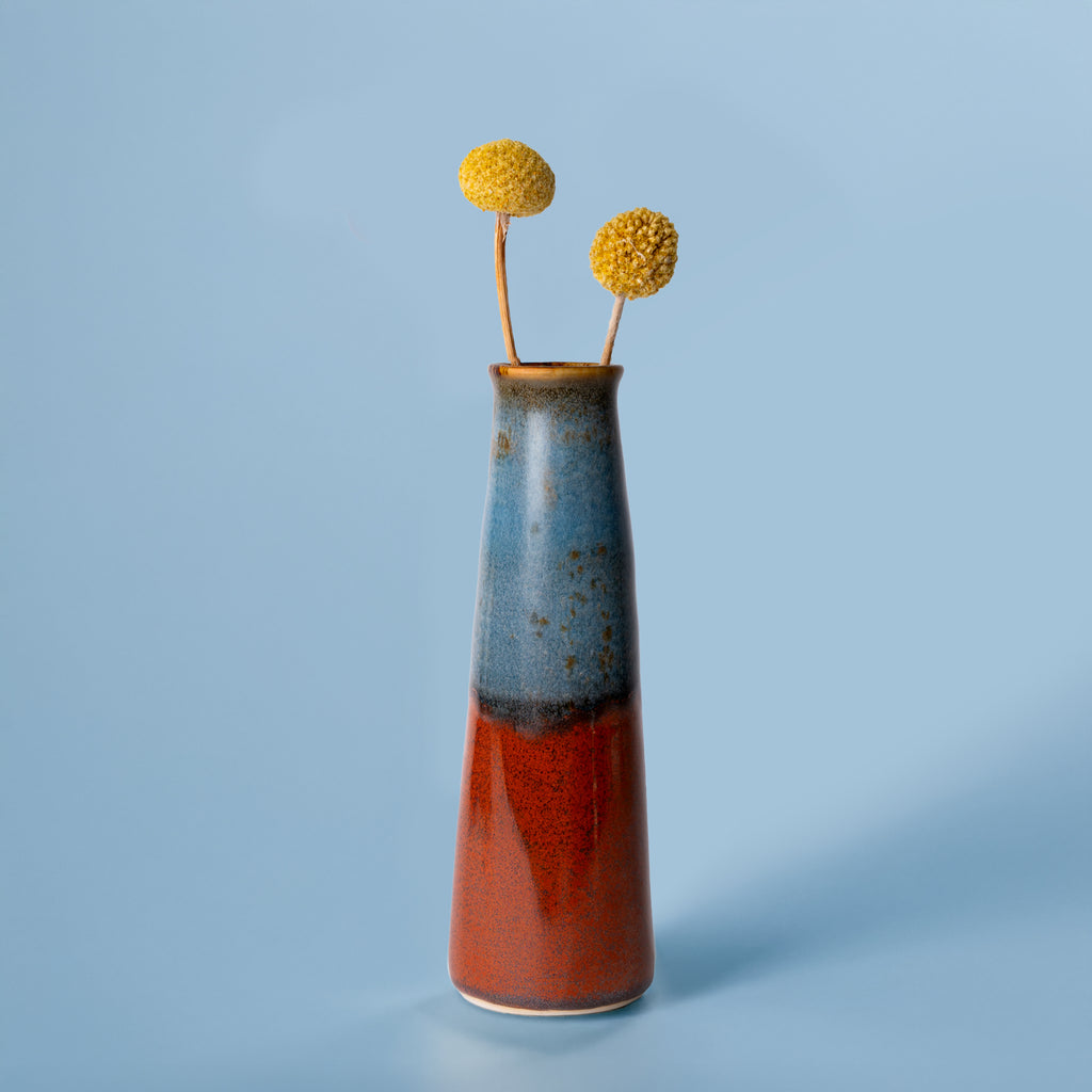 Pottery For The Planet tall ceramic sustainable home decor vase with blue and red glaze holding yellow billy ball flowers