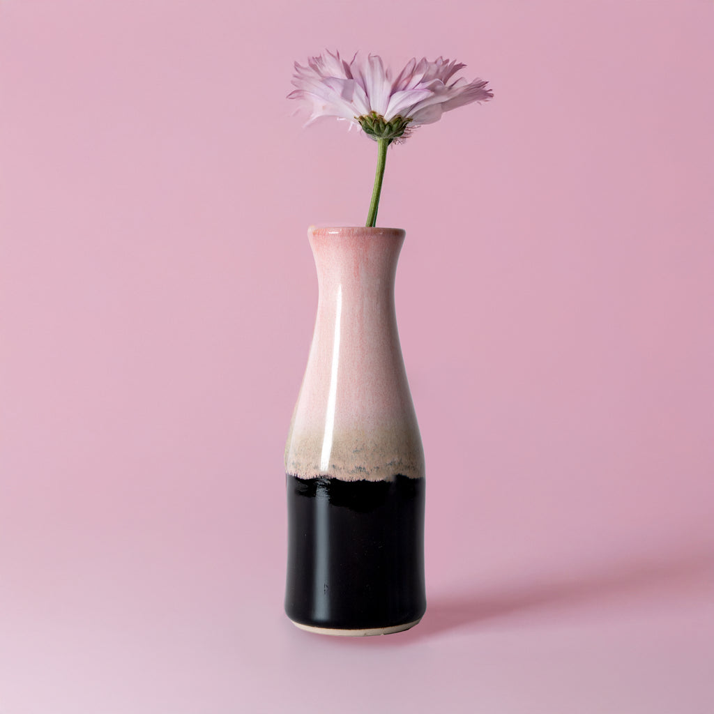 Unique ceramic flower vase by Pottery For The Planet with pink and black glaze holding a single flower