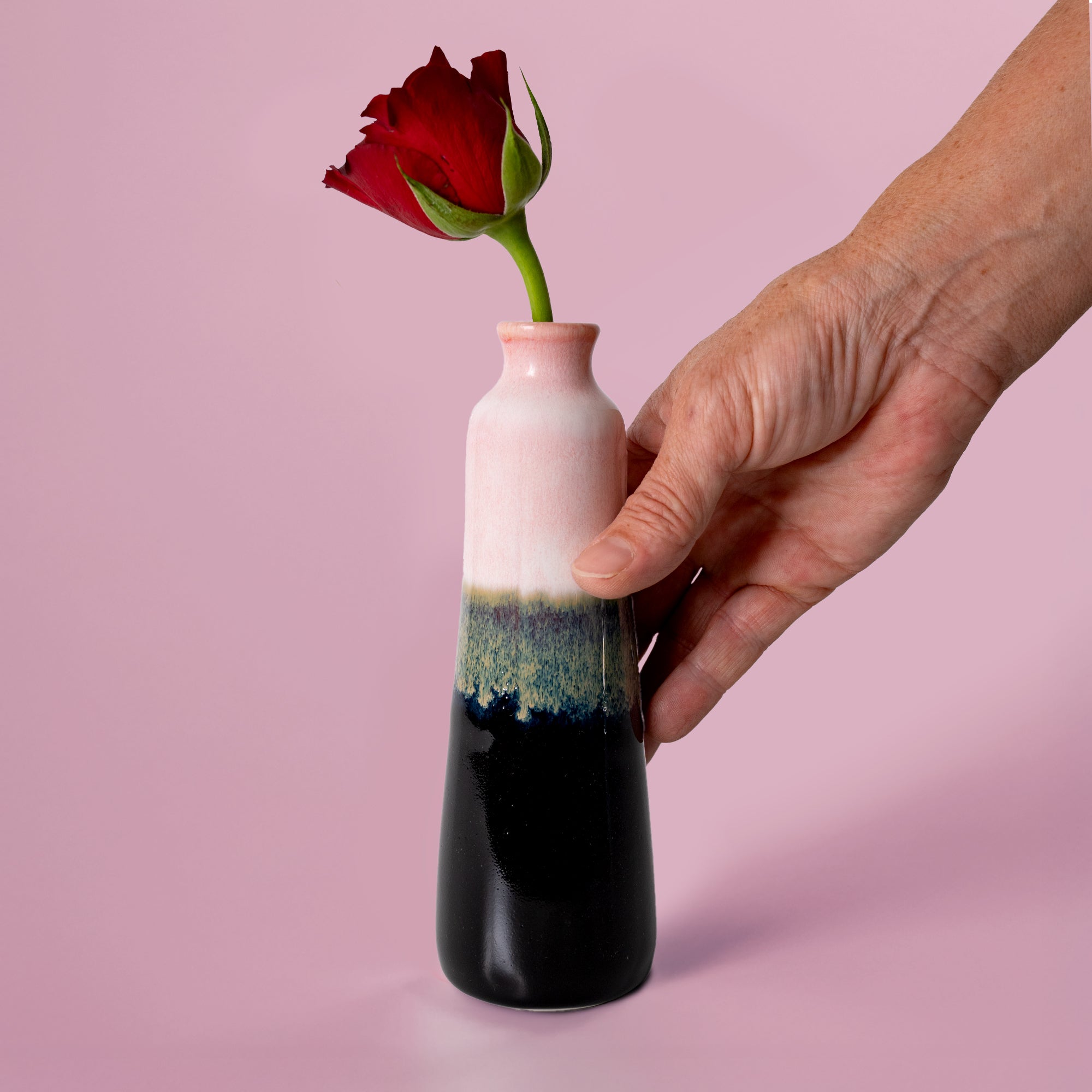Unique handmade ceramic vase by Pottery For The Planet with a red flower held against a pink background