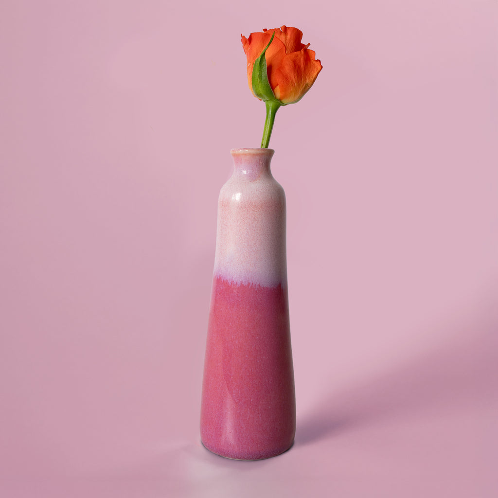 Unique handmade ceramic vase by Pottery For The Planet with pink gradient holding an orange rose
