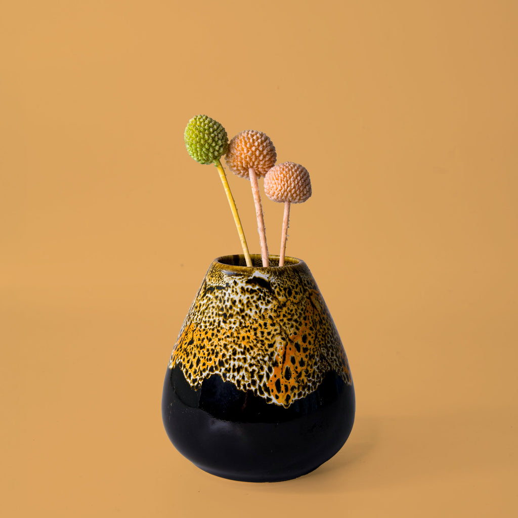 Unique pottery flower vase from Pottery For The Planet with a speckled yellow and black design holding decorative flowers