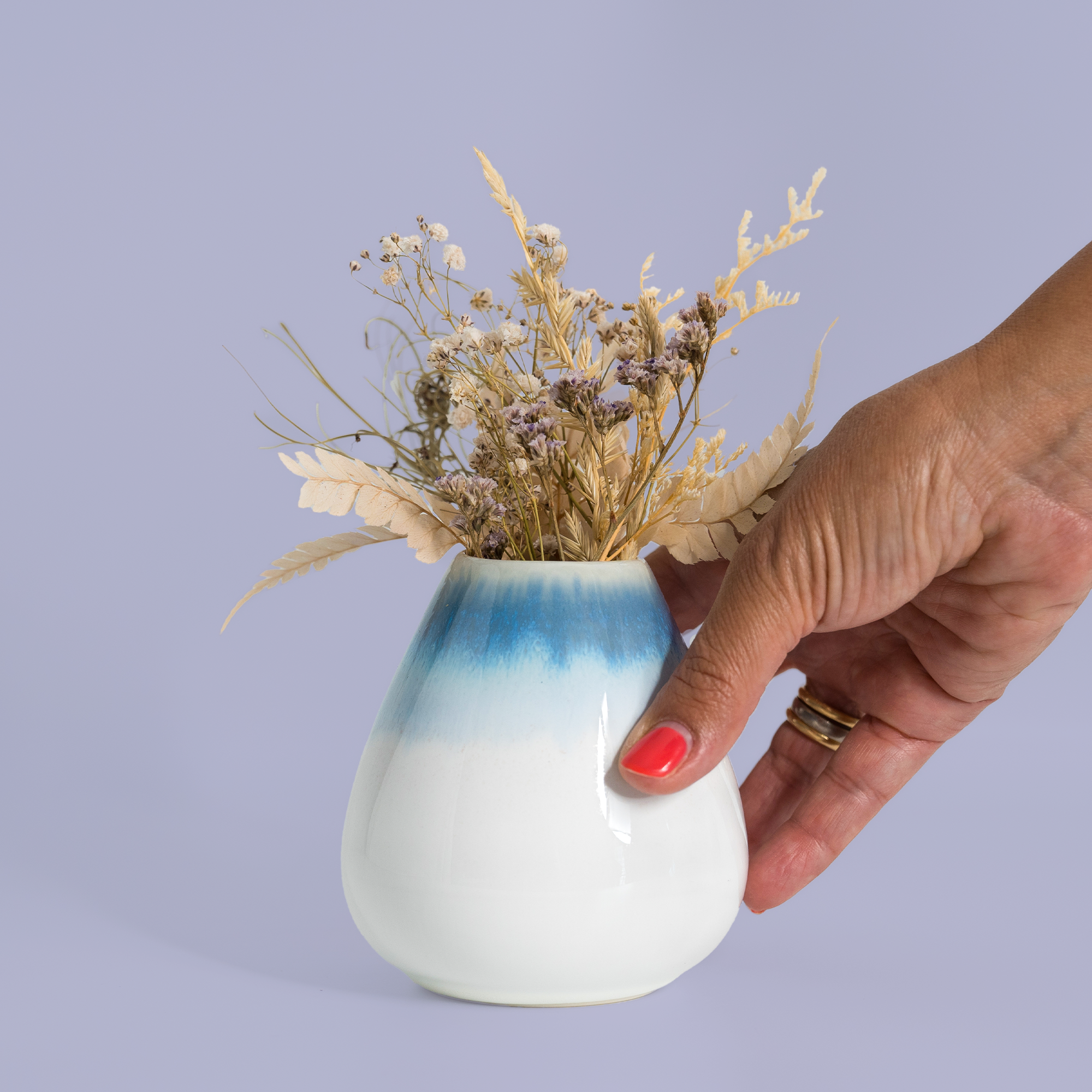 Hand holding unique pottery flower vase in white and blue with dried flowers by Pottery For The Planet
