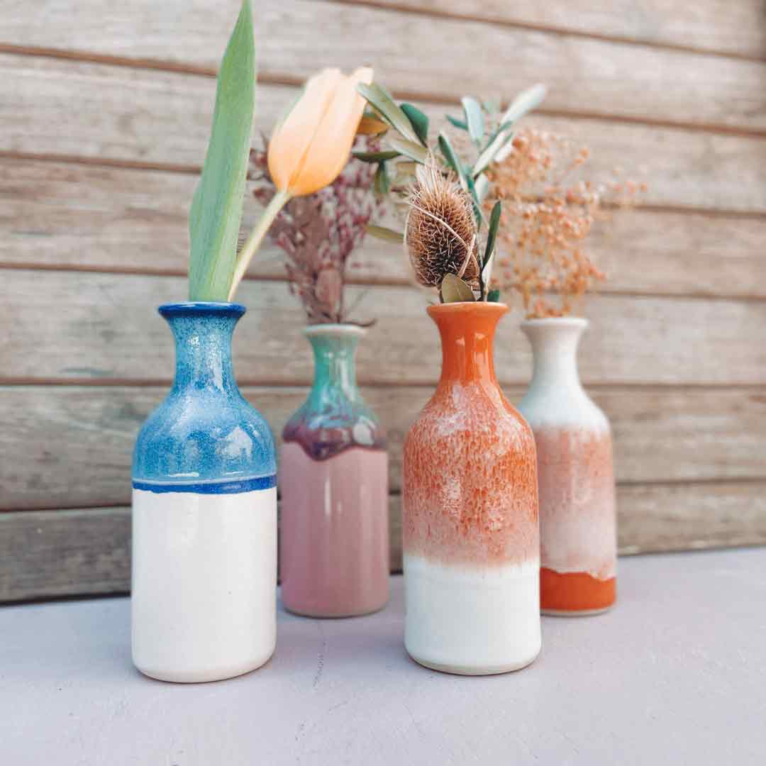 Juniper Vases in Diverse range of colours with flowers against a wooden wall